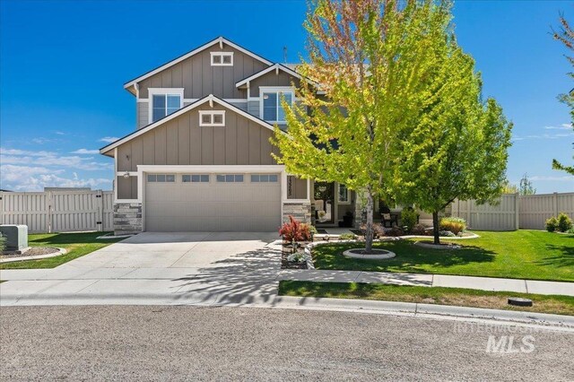 craftsman-style house with board and batten siding, fence, concrete driveway, an attached garage, and stone siding