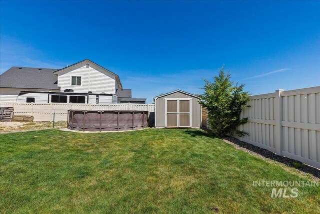view of yard featuring a storage shed, a fenced in pool, an outdoor structure, and a fenced backyard