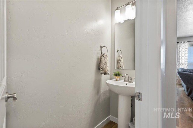 half bath with baseboards and a sink