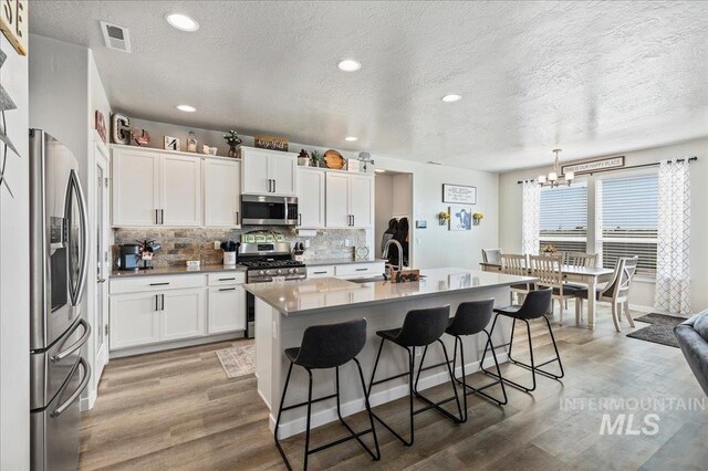 kitchen with light wood-type flooring, a sink, a breakfast bar area, and stainless steel appliances