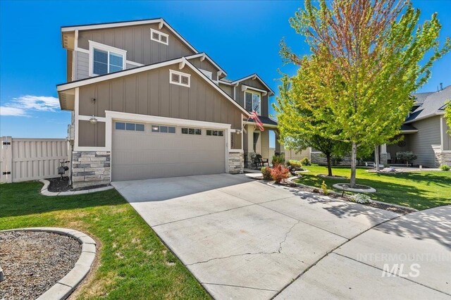 craftsman inspired home featuring fence, a front lawn, stone siding, board and batten siding, and concrete driveway