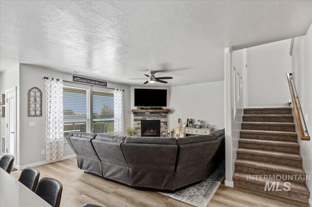 living room featuring a ceiling fan, light wood finished floors, and a textured ceiling