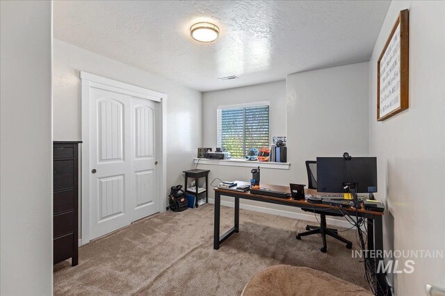 carpeted office space with a textured ceiling and visible vents