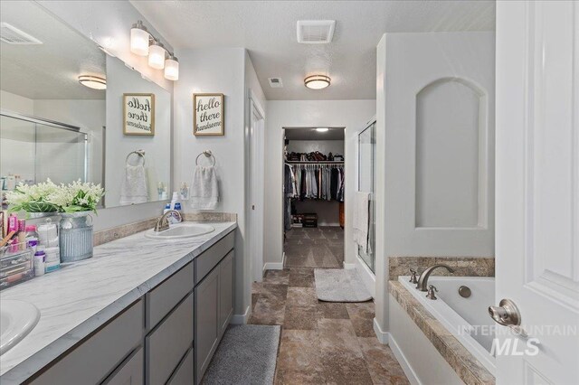 bathroom with a sink, double vanity, stone finish floor, visible vents, and a stall shower