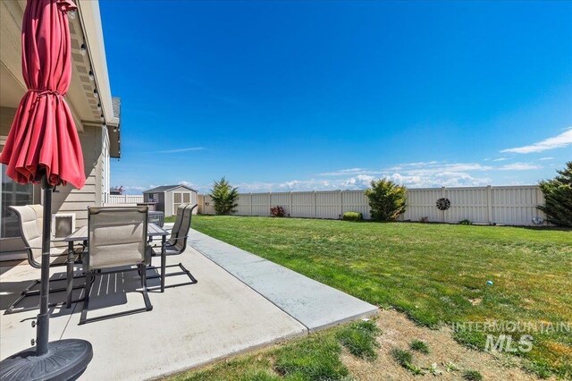 view of yard with an outdoor structure, outdoor dining area, a fenced backyard, a patio area, and a storage shed