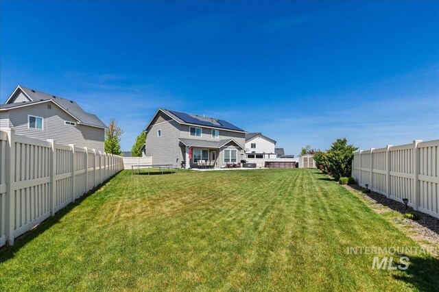 rear view of property featuring a fenced backyard, a trampoline, a yard, and a patio area