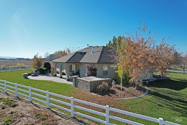 exterior space featuring a rural view, a lawn, and a patio area