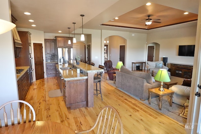 924 Main St S, Kimberly, ID 83341 - kitchen with arched walkways, stainless steel refrigerator with ice dispenser, light wood finished floors, open floor plan, and ceiling fan