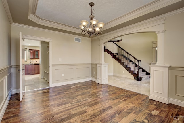 spare room with decorative columns, an inviting chandelier, ornamental molding, and a tray ceiling