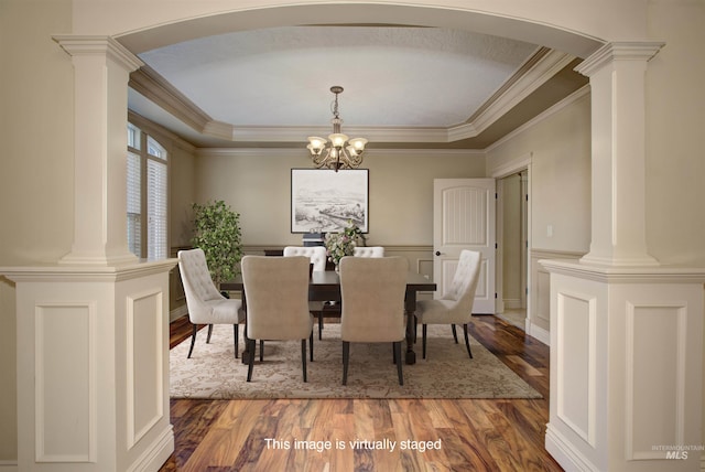 dining room featuring a raised ceiling, an inviting chandelier, ornamental molding, and hardwood / wood-style flooring