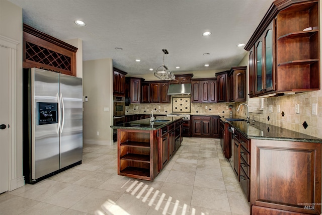 kitchen featuring an island with sink, light tile patterned floors, appliances with stainless steel finishes, dark brown cabinets, and sink