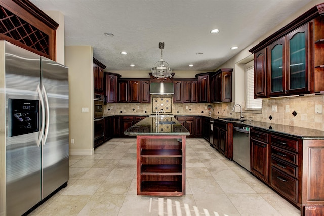 kitchen featuring pendant lighting, a kitchen island with sink, appliances with stainless steel finishes, dark stone countertops, and sink