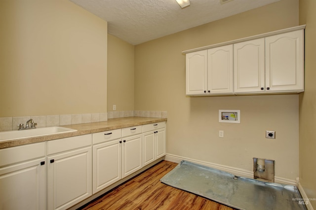 clothes washing area with cabinets, a textured ceiling, washer hookup, electric dryer hookup, and sink