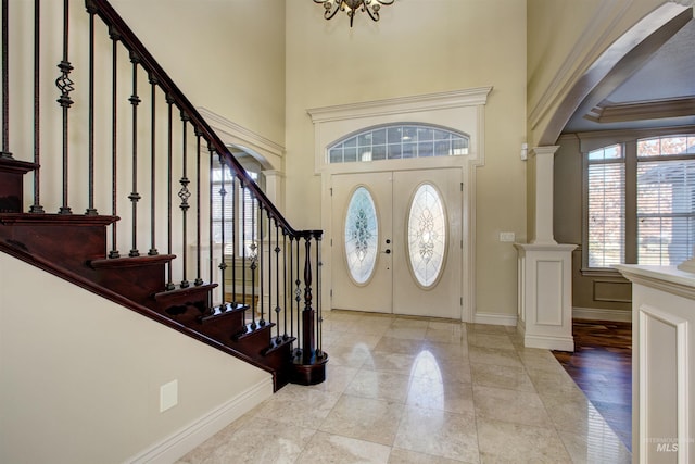 foyer with a notable chandelier, french doors, and ornate columns