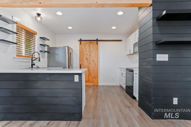 511 N 10th Ave N, Nampa, ID 83687 - kitchen featuring open shelves, black appliances, a barn door, light wood-style floors, and light countertops