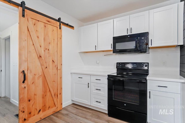 511 N 10th Ave N, Nampa, ID 83687 - kitchen featuring black appliances, a barn door, light wood-style floors, and white cabinets