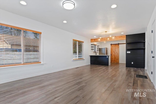 511 N 10th Ave N, Nampa, ID 83687 - unfurnished living room featuring a barn door, wood finished floors, baseboards, and recessed lighting