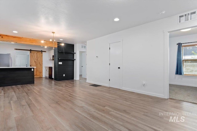 511 N 10th Ave N, Nampa, ID 83687 - unfurnished living room featuring a barn door, light wood-style floors, baseboards, and recessed lighting