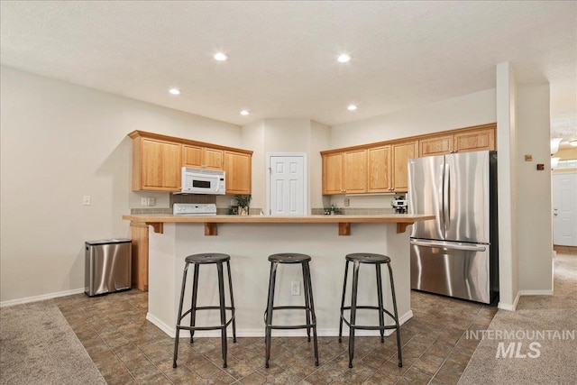 9425 W Java Ct, Boise, ID 83704 - kitchen featuring freestanding refrigerator, white microwave, light countertops, a kitchen breakfast bar, and recessed lighting