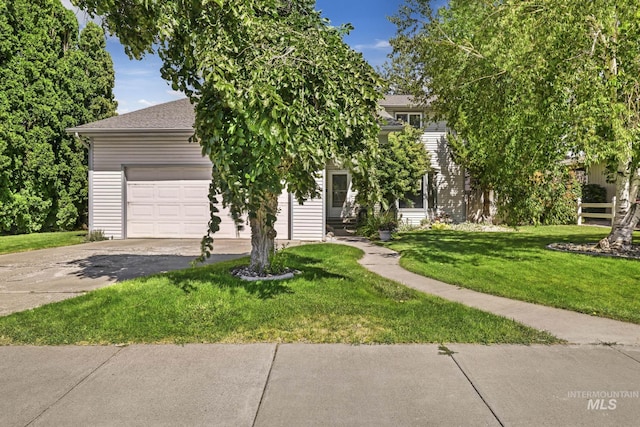 view of property hidden behind natural elements with a garage, concrete driveway, and a front yard