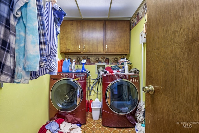 clothes washing area featuring cabinet space and washer and clothes dryer