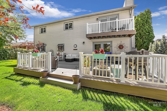 back of property with a yard, a chimney, outdoor lounge area, a balcony, and a wooden deck