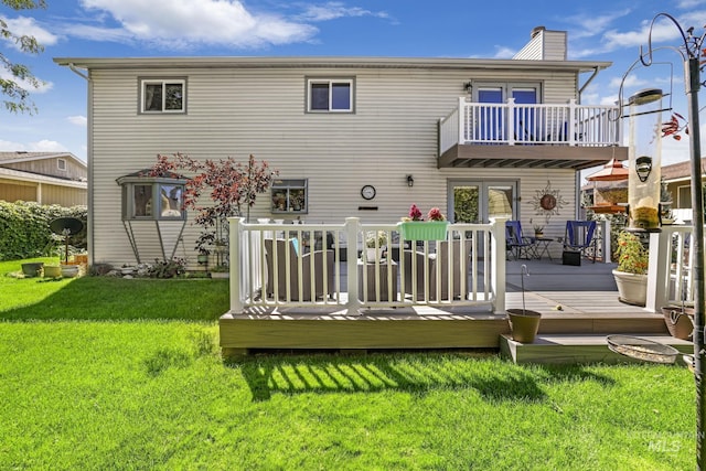 back of house with a balcony, a yard, a chimney, and a wooden deck