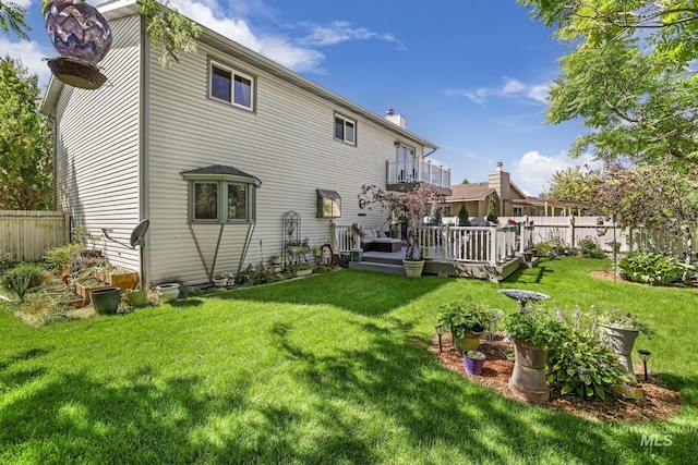 back of property featuring fence, a lawn, and a wooden deck