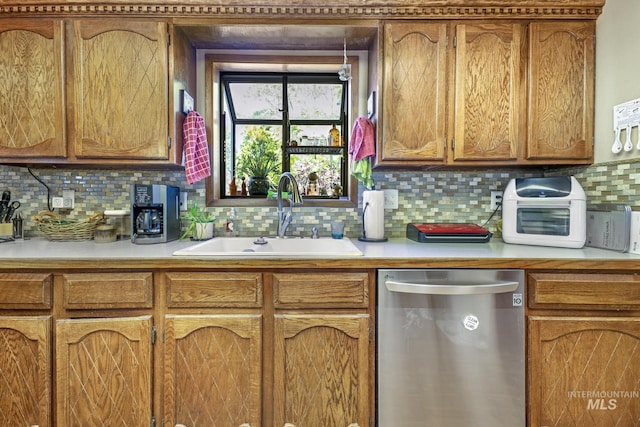 kitchen with brown cabinets, light countertops, decorative backsplash, stainless steel dishwasher, and a sink