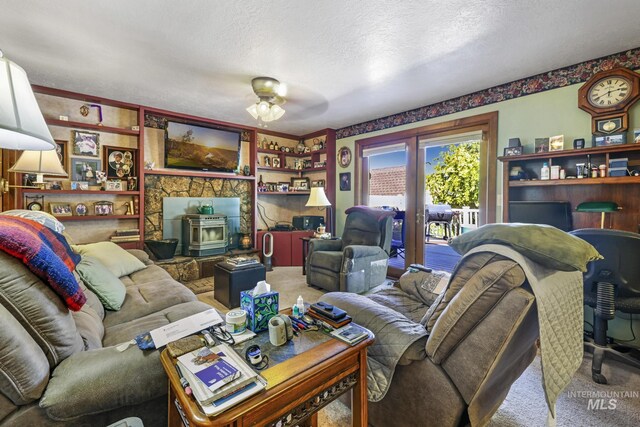 living area with carpet, a wood stove, a textured ceiling, and french doors