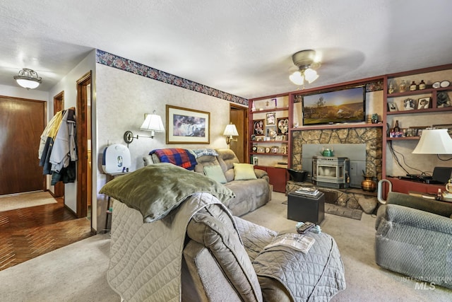 living area with a wood stove, ceiling fan, carpet floors, and a textured ceiling