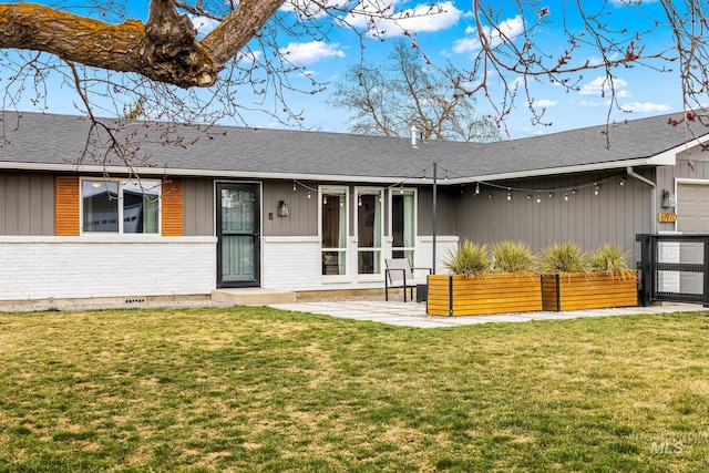 exterior space featuring brick siding, a shingled roof, and a front yard