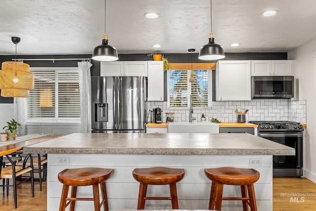 kitchen featuring backsplash, appliances with stainless steel finishes, light wood-type flooring, and a sink