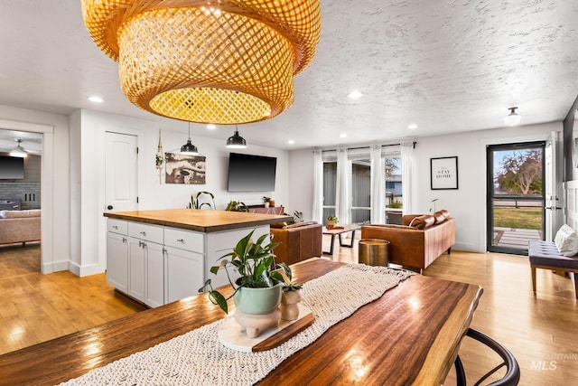 dining room featuring recessed lighting, light wood-style floors, and a textured ceiling