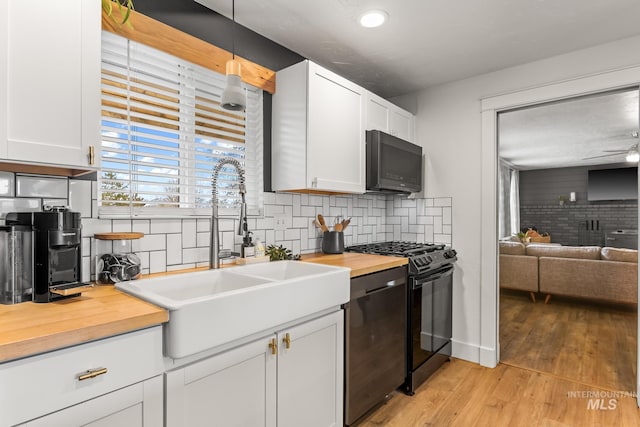 kitchen featuring a sink, tasteful backsplash, black gas stove, and butcher block counters