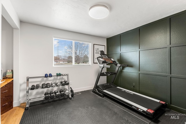 exercise area with baseboards and a decorative wall