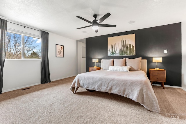 carpeted bedroom featuring visible vents, baseboards, a textured ceiling, and ceiling fan