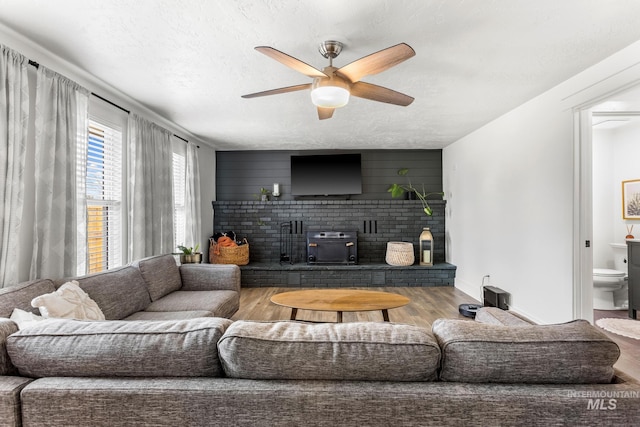 living room with baseboards, a textured ceiling, wood finished floors, and a ceiling fan