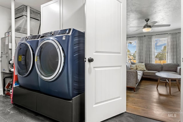 clothes washing area with washing machine and clothes dryer, cabinet space, a textured ceiling, a ceiling fan, and dark wood-style flooring