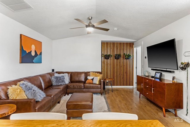 living area with wood finished floors, visible vents, lofted ceiling, ceiling fan, and a textured ceiling