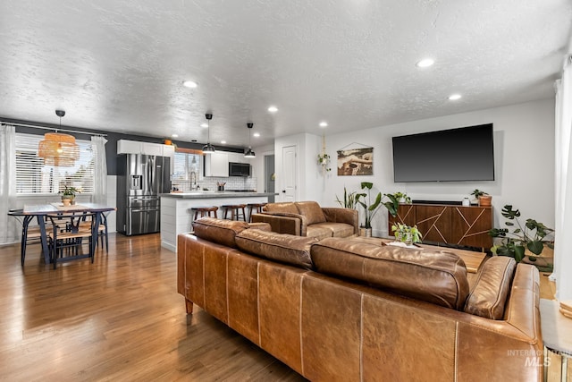 living room featuring recessed lighting, a textured ceiling, and wood finished floors