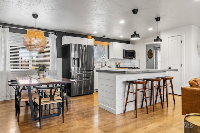 kitchen featuring light wood-type flooring, stainless steel appliances, and tasteful backsplash