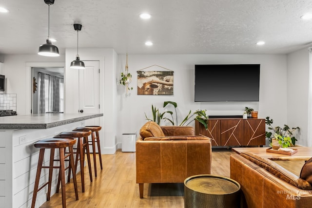 living area with recessed lighting, light wood-style floors, and a textured ceiling