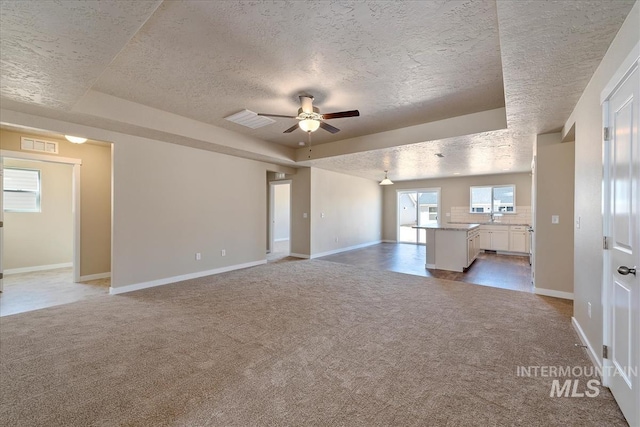 19144 Red Eagle Way, Caldwell, ID 83605 - unfurnished living room featuring light colored carpet, visible vents, ceiling fan, and a raised ceiling