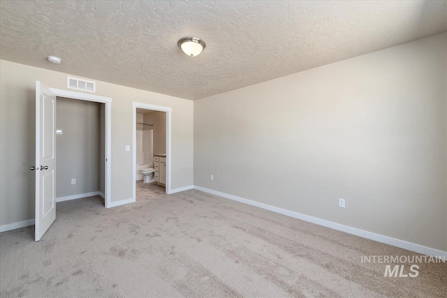 19144 Red Eagle Way, Caldwell, ID 83605 - unfurnished bedroom with a textured ceiling, ensuite bathroom, baseboards, light colored carpet, and visible vents