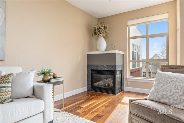 living room with a glass covered fireplace, wood finished floors, and baseboards