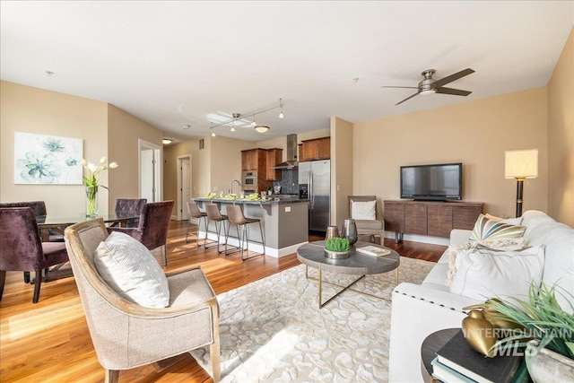 living room featuring a ceiling fan, visible vents, and light wood finished floors