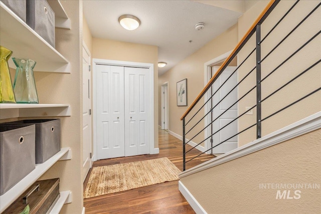 entryway with baseboards, stairway, and wood finished floors