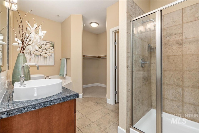 full bath featuring vanity, baseboards, a shower stall, tile patterned floors, and a walk in closet