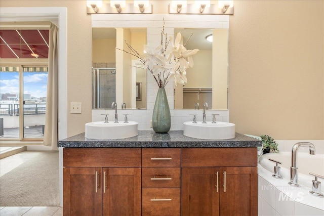 full bath with double vanity, a stall shower, decorative backsplash, and a sink